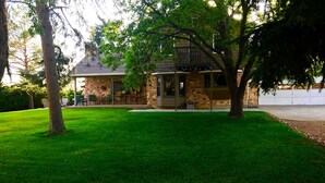 A stone building with a covered patio and a well-maintained lawn. - 5-bedroom vacation home Mead,Co. /Easily access I-25 DenverBoulderFtCollinsEstes (Mead)