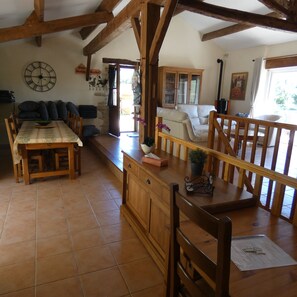 A rustic interior with a wooden dining table, a sofa, and a staircase.