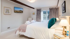 Un dormitorio con cama, una mesita de noche con lámpara, una ventana con cortinas y obras de arte en las paredes.