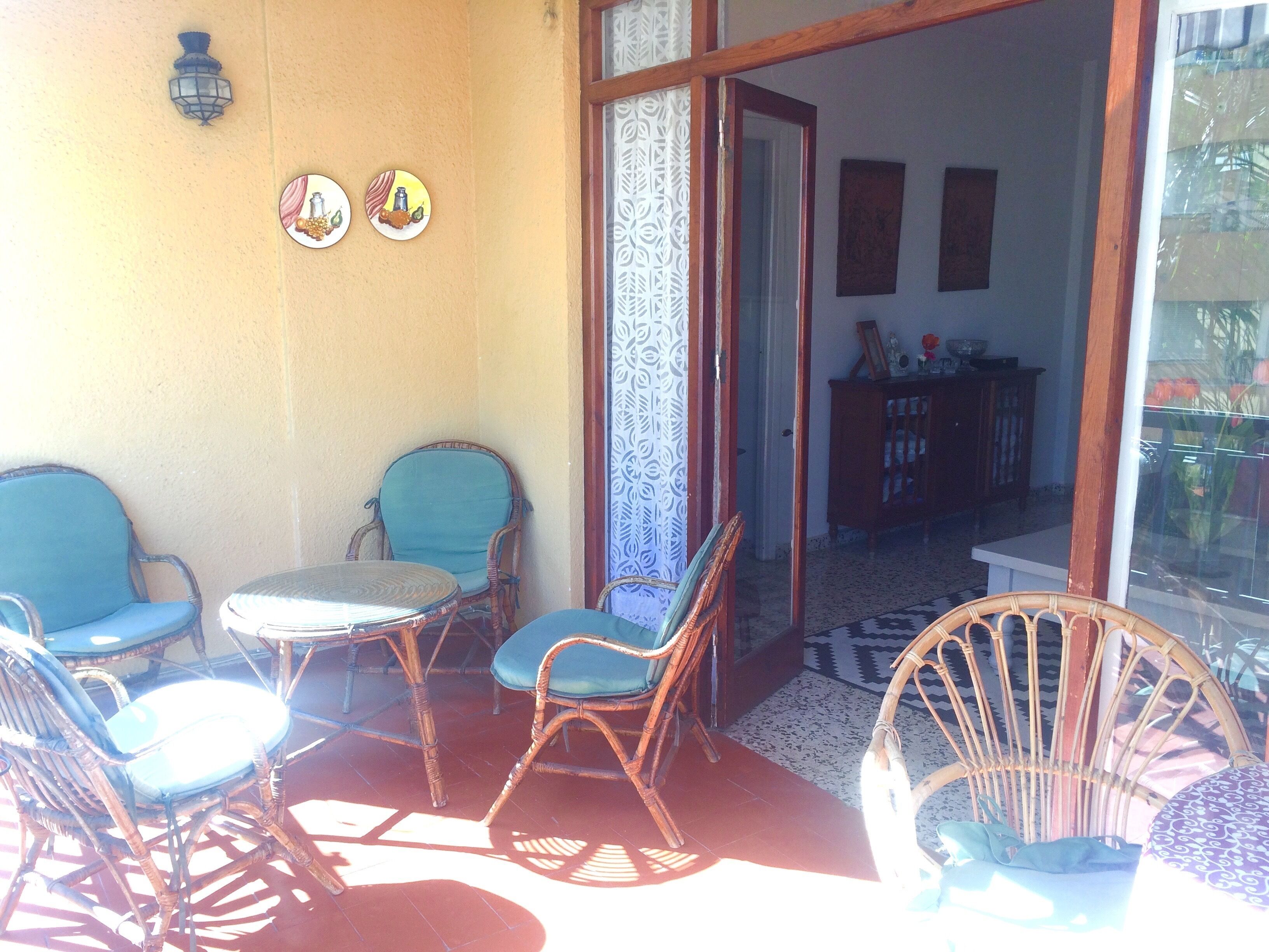 Un patio soleggiato con mobili in vimini e una tenda decorata.