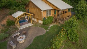 Eine Holzhütte mit einer Terrasse, einem Whirlpool und einer Feuerstelle.