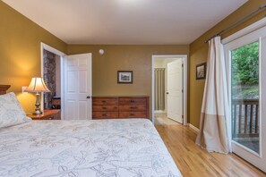 A bedroom with a bed, dresser, and a door leading to a balcony. - Hot Tub+Fire Pit, Grill, Fireplace, WiFi, Private! (Burnsville)