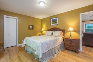 A bedroom with a bed, two bedside tables with lamps, a door, and a framed picture on the wall. - Hot Tub+Fire Pit, Grill, Fireplace, WiFi, Private! (Burnsville)