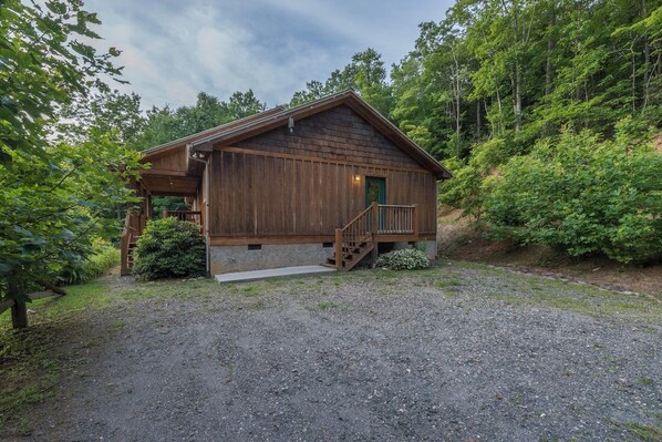 A wooden cabin with a porch and a staircase leading to the entrance.