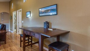 Ein Arbeitszimmer mit Schreibtisch aus Holz, einem Sessel und einem gerahmten Bild an der Wand.