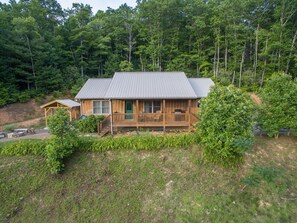 A cabin with a porch, surrounded by dense forest.