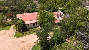 Ein Landhaus mit rotem Dach, umgeben von dichtem Grün und einer Windmühle.