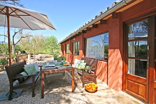 An outdoor patio with a wooden table, chairs, and a large umbrella.