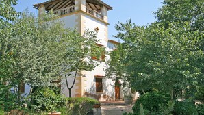 A traditional building with a tower, surrounded by lush greenery and a clear sky. - Sa Torre: Idyllic estate, individual areas, garden, pool, WiFi, air conditioning (Santa Maria del Cami)