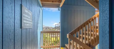 Un escalier en bois menant à un balcon sur lequel est affiché un panneau indiquant : « Veuillez faire silence ».