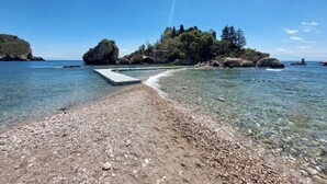 A pebble beach leading to a rocky island with clear water and a pier. - Villette Taormina, La Perla Dell'isola (Taormina)