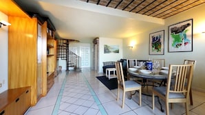 A spacious living area with a dining table set for four, a staircase leading to an upper floor, and a cozy seating area with a sofa and chairs. - Villette Taormina, La Perla Dell'isola (Taormina)