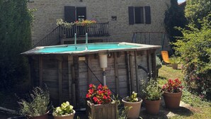Een stenen gebouw met een zwembad, omringd door potplanten en een gazon.