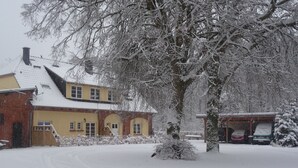 Un barrio residencial cubierto de nieve, con una casa, un garaje y un árbol.