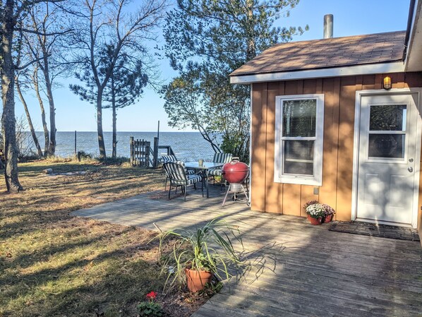 A wooden deck with outdoor furniture, a barbecue grill, and a small shed.