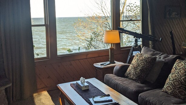 Una sala acogedora con vista al agua, un sofá, una mesa de centro y una lámpara.