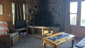 Una sala de estar acogedora con chimenea de piedra, muebles de madera y televisor.