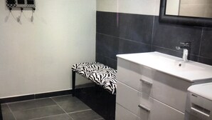 Ein Badezimmer mit einer Sitzbank in Zebra-Optik, einem weißen Waschbecken und einem Spiegel darüber.