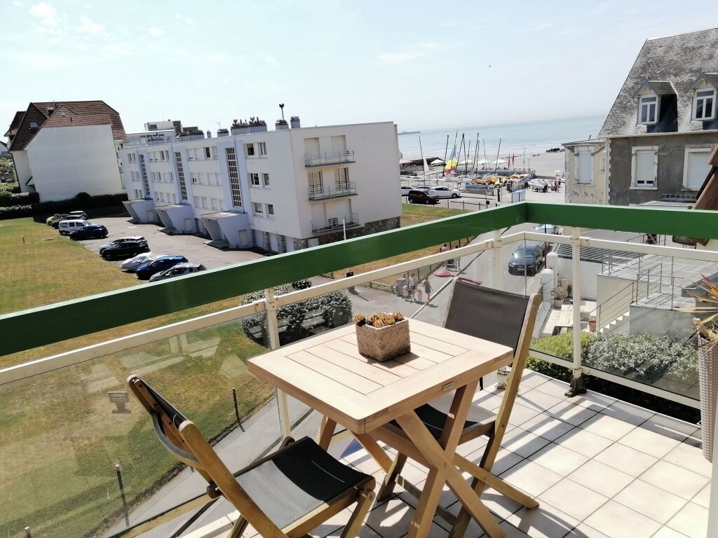 Un balcó amb taula i cadires, amb vistes a una zona d'aparcament i edificis.