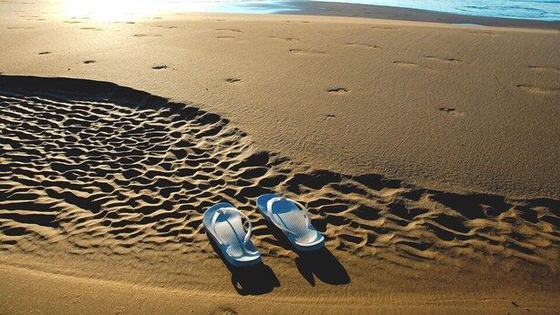 A pair of flip-flops on a sandy beach with footprints leading to the water. - t2 + air conditioned cabin with garden 4 pers, gruissan village (Gruissan)