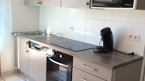A modern kitchen with a built-in dishwasher, oven, and microwave. - t2 + air conditioned cabin with garden 4 pers, gruissan village (Gruissan)