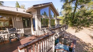 A cabin with a deck, a hot tub, and a grill area. - Fort Rock-Wonderful Sunriver Home,3BR-3.5BA- Hot Tub- Wifi-8 SHARC passes (Sunriver)