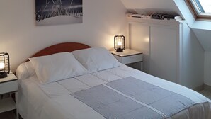 Ett sovrum med en säng, ett sängbord, en sänglampa, en tavla som hänger på väggen och ett takfönster.