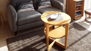 Ett mysigt vardagsrum med en grå soffa, ett litet träbord och inramade tavlor på väggen.