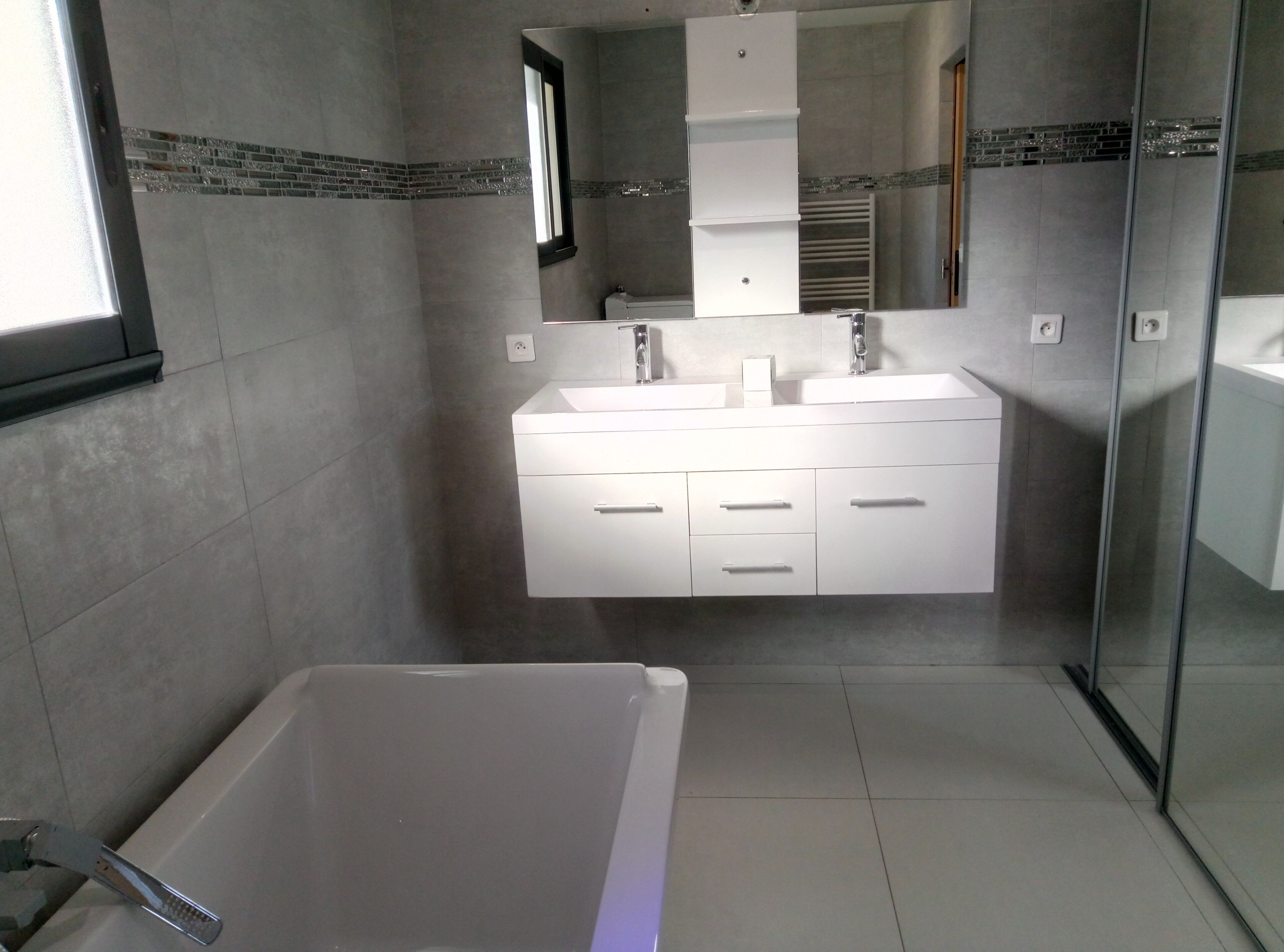 A modern bathroom with a large bathtub, a double sink vanity, and a glass shower enclosure.