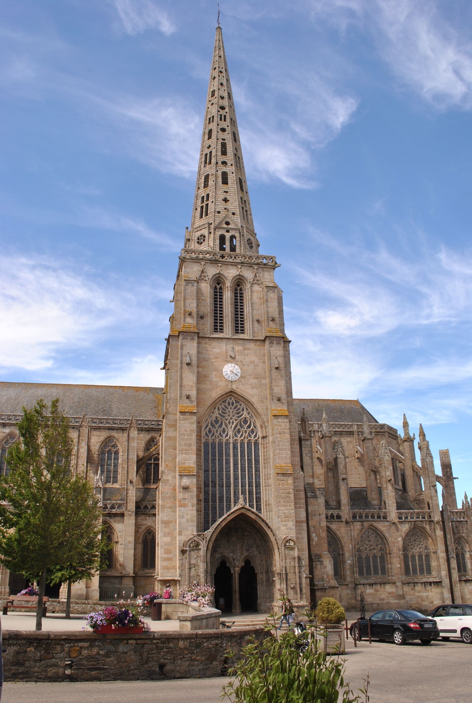 A large cathedral with a tall spire, large arched windows, and a clock on the front facade.