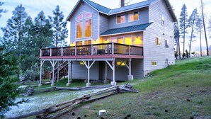 A two-story house with a balcony, surrounded by trees.