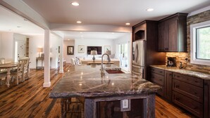 A spacious kitchen with a marble island, dark wooden cabinets, and a large window providing natural light. - 36 Private Acres on the New River (Boone)