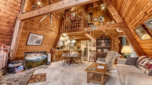 A cozy, wooden interior with a dining area, a living room with a sofa and armchairs, and a staircase leading to an upper level. - 2 Miles to National Park or Downtown Gatlinburg! Less than1/2 mile to Ober! (Gatlinburg)