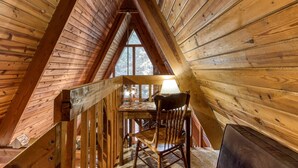 A wooden interior with a sloped ceiling, a wooden table, a chair, and a window providing a view of trees. - 2 Miles to National Park or Downtown Gatlinburg! Less than1/2 mile to Ober! (Gatlinburg)