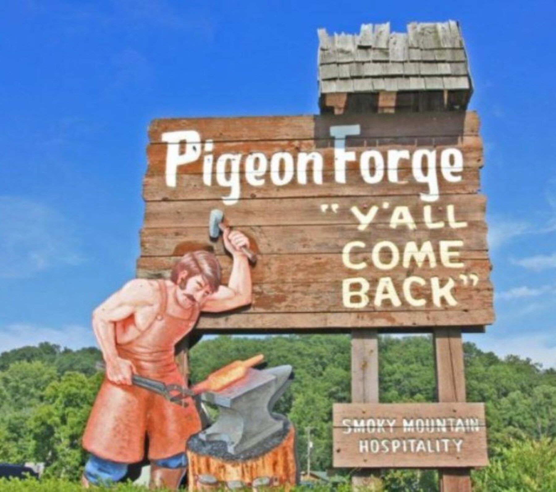 Une enseigne en bois ornée d’une illustration représentant un forgeron et portant l’inscription : « Pigeon Forge, revenez-nous, l’hospitalité des Monts Rocheux vous attend. »