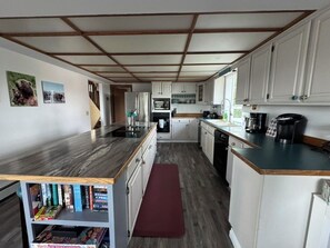 Een kleine keuken met witte kastjes, een houten aanrechtblad en een ingebouwde boekenkast.