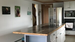 A modern kitchen with a wooden countertop, stainless steel appliances, and white cabinetry.