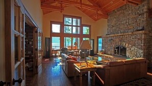 A spacious living room with a stone fireplace, large windows, and a cozy seating area. - The Most Beautiful House on Flathead Lake - NW Travel Magazine 'Best Waterfront' (Polson)