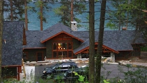 A lodge with a stone chimney, wooden exterior, and a view of a lake. - The Most Beautiful House on Flathead Lake - NW Travel Magazine 'Best Waterfront' (Polson)