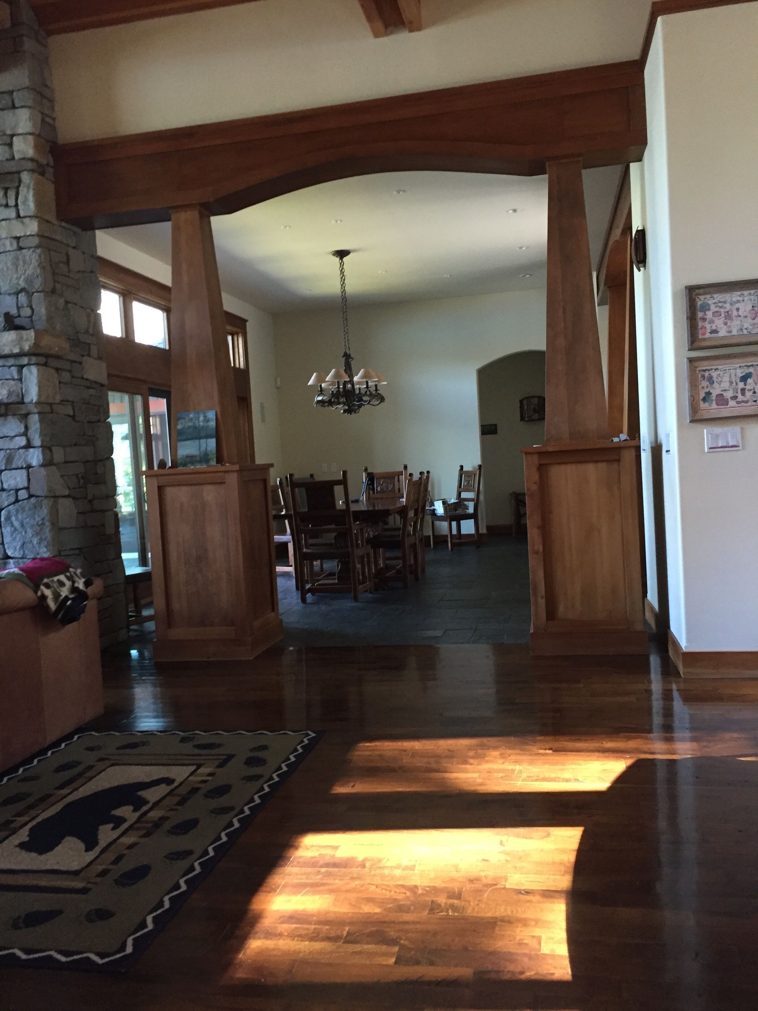 A spacious interior with a wooden floor, stone pillar, and a chandelier.