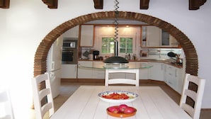 Una cucina con isola in vetro, mobili bianchi e un arco in mattoni.