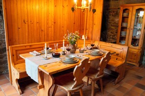 Un tavolo da pranzo in legno apparecchiato con piatti, bicchieri e un vaso di fiori.