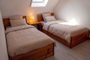 A bedroom with two wooden beds, a nightstand with a lamp, and a skylight. - Breton stone house, in a quiet location and the beach (Landéda)