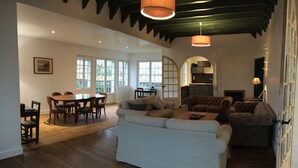 A spacious living area with a dining table, sofas, and a colorful striped rug. - Family villa in Noirmoutier (175 m2, sleeps 11) (Noirmoutier)