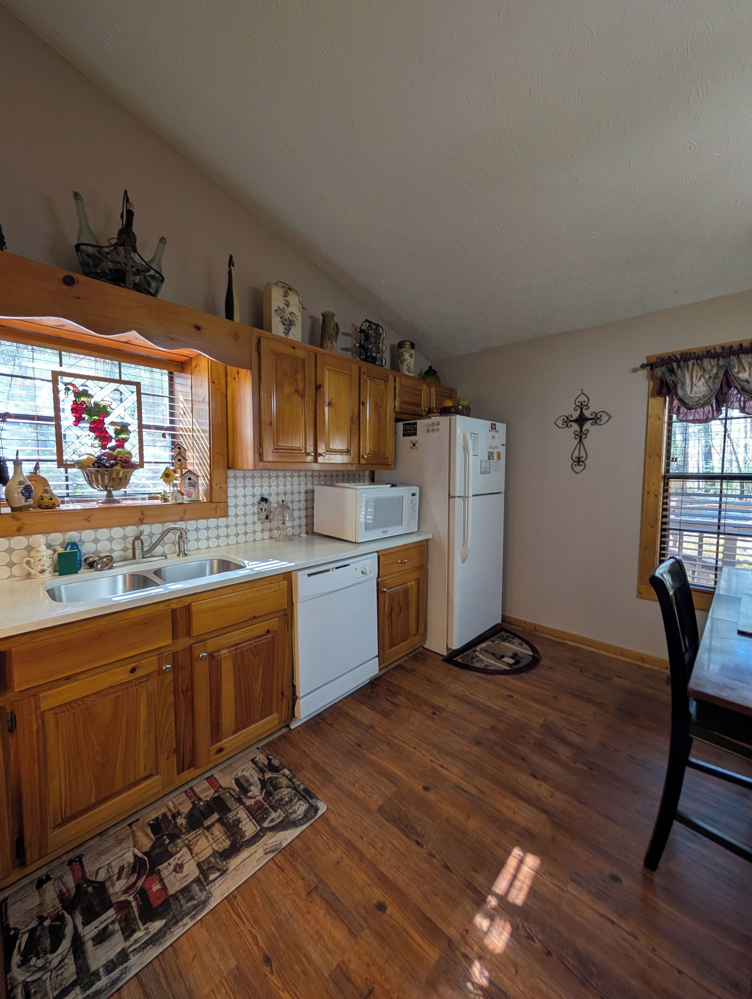 A kitchen with wooden cabinets, a white microwave, and a refrigerator.