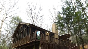 Eine Hütte mit Balkon, Holelllaufgeländern und einer Treppe zum Eingang.