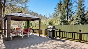 A covered outdoor patio with a table and chairs, a grill, and a wooden deck. - Five Star Home 2 miles from Biltmore Estate  (Asheville)