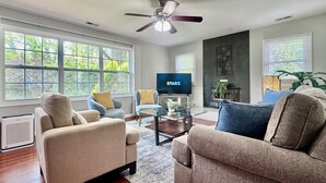 A living room with a ceiling fan, a television, and a fireplace. - Five Star Home 2 miles from Biltmore Estate  (Asheville)