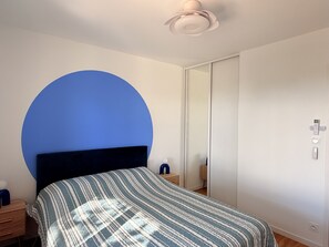 Un dormitorio con cama, mesita de noche, armario y lámpara en el techo.