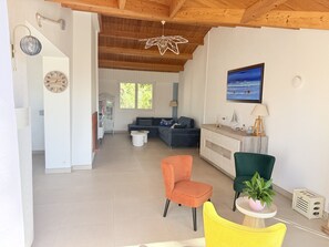 A spacious living area with a wooden ceiling, a blue sofa, a yellow chair, and a green chair.